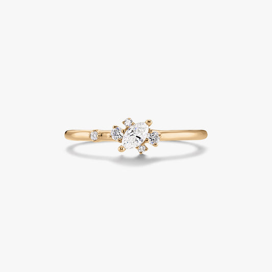 Jemný prsten ze žlutého zlata 14K se středovým diamantem brusu marquise a malými kulatými akcentními diamanty na bílém pozadí.