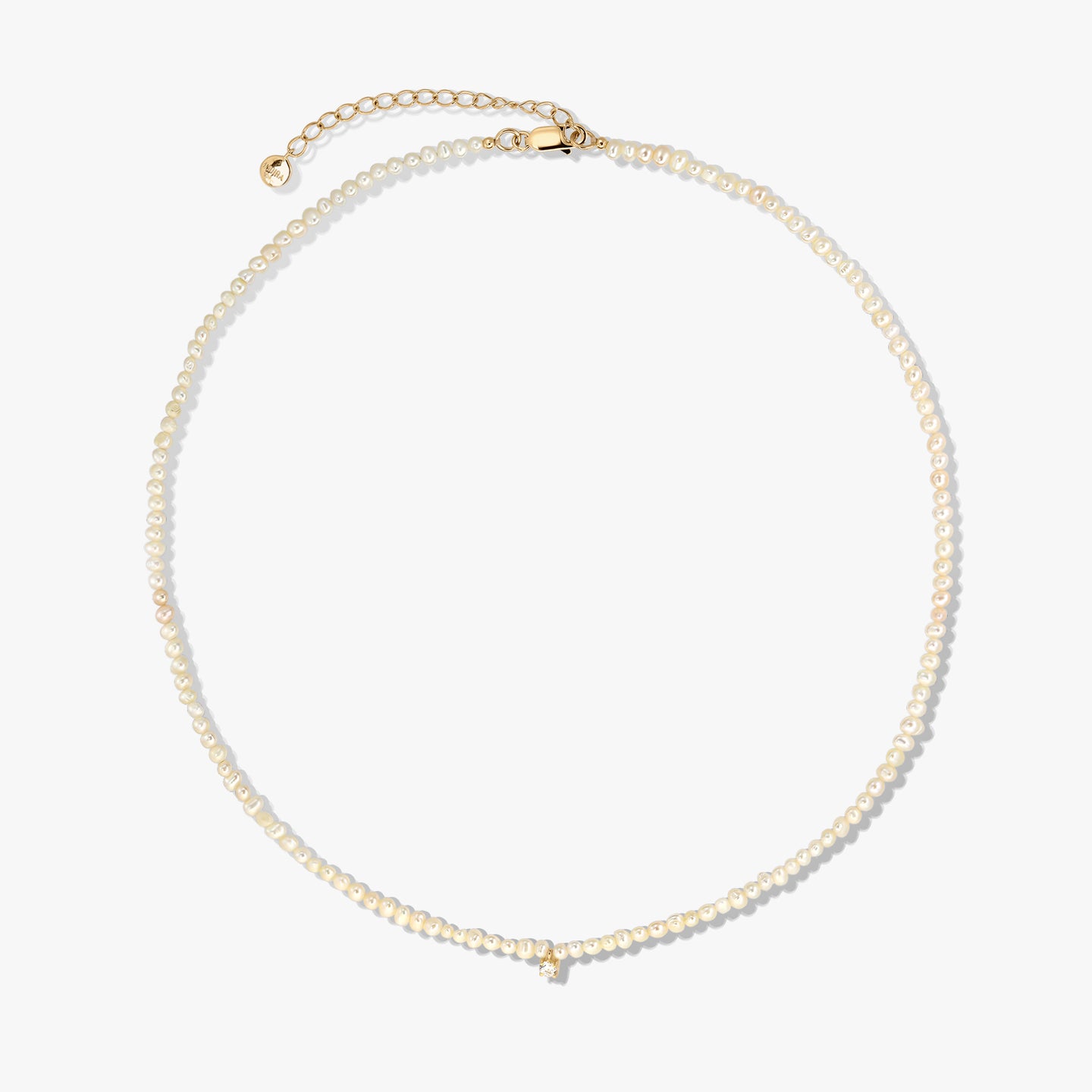 Delicate cultured pearl beaded necklace with a gold-plated sterling silver clasp and extender, photographed on a white background.