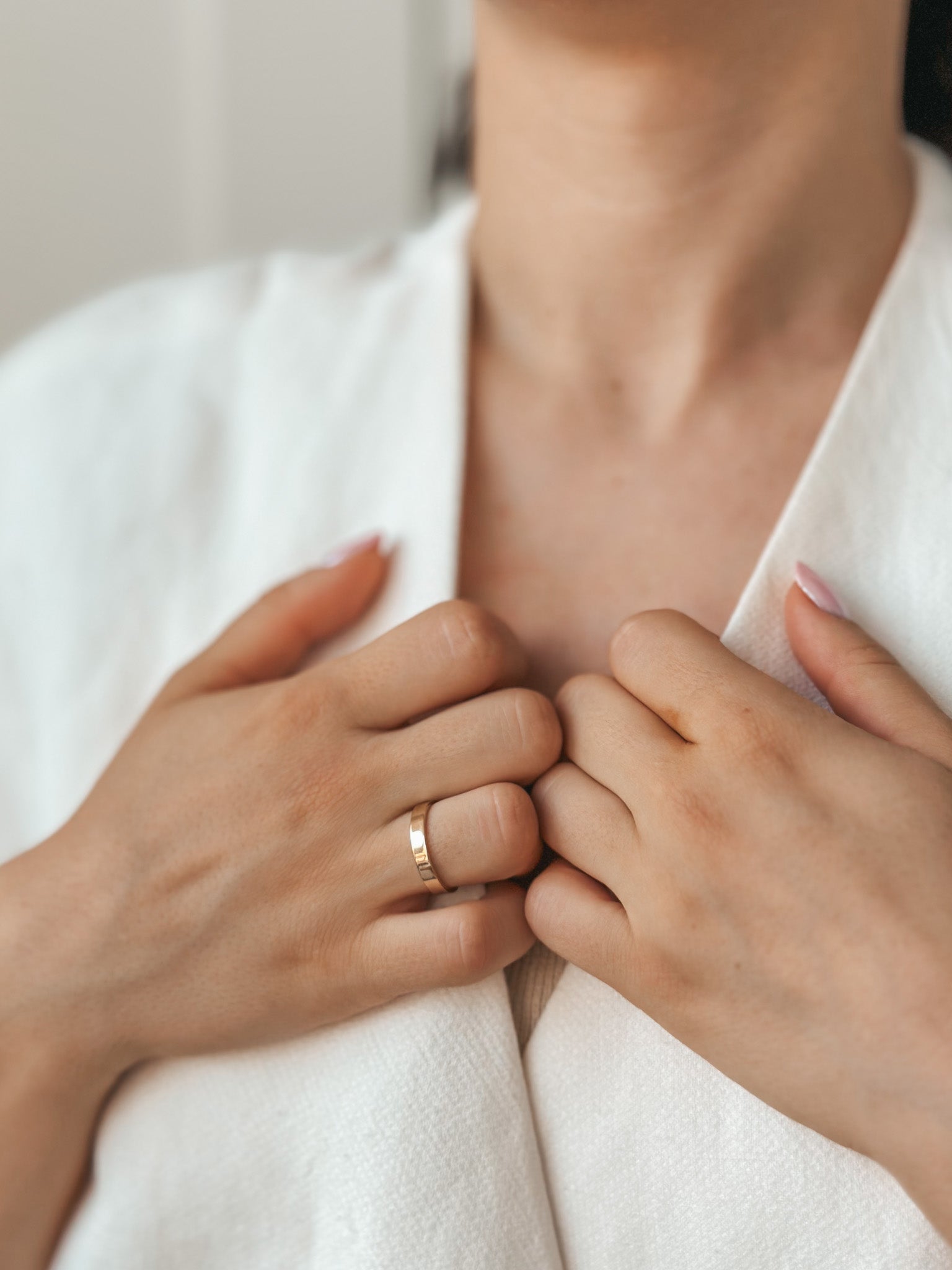 Close-up of hands holding a garment, featuring a gold wedding band on one finger.