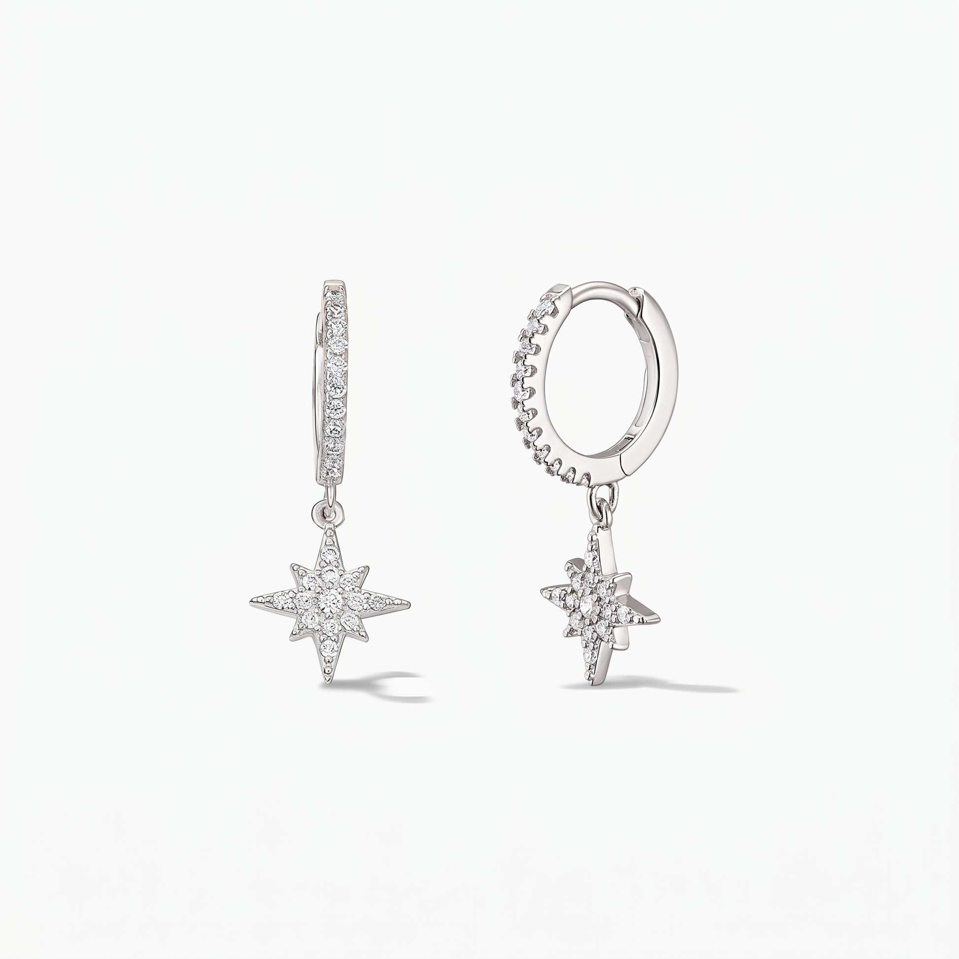 Pair of 925 sterling-silver huggie hoop earrings with pavé white zirconia North Star charms on a white background.