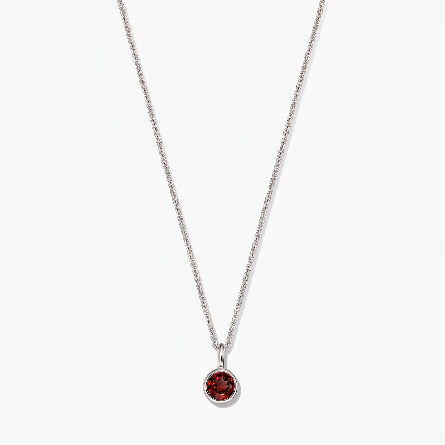 Sterling silver birthstone necklace with a round bezel‑set garnet pendant on a white background.
