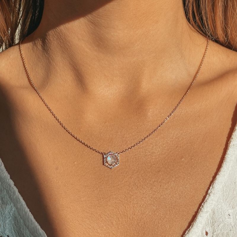 Close-up of a woman's neck wearing a rose silver necklace with a moonstone pendant.