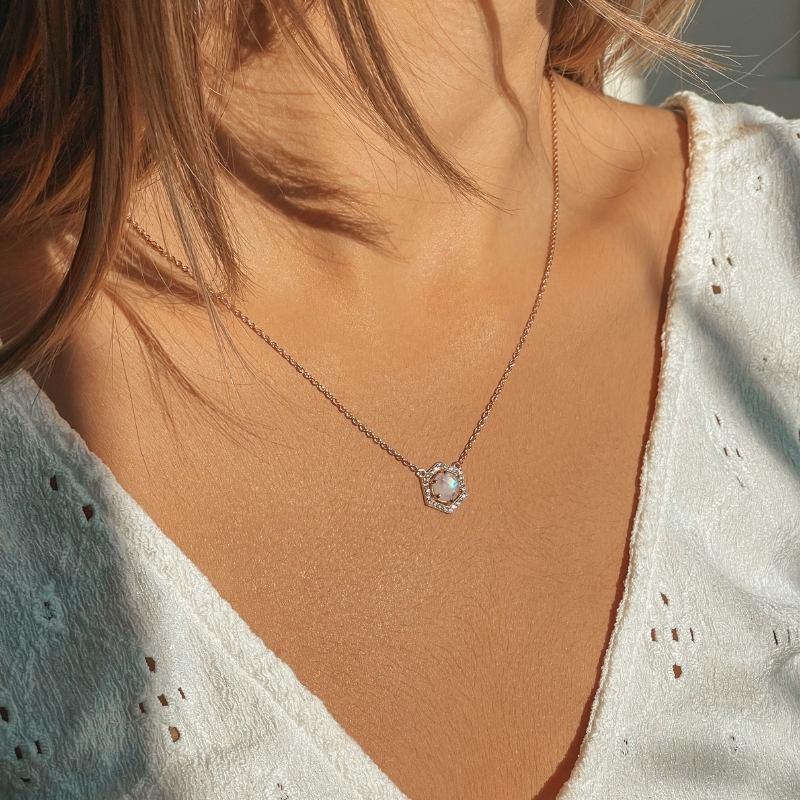 Woman wearing a rose silver necklace with a moonstone pendant, close-up on neck and jewelry.