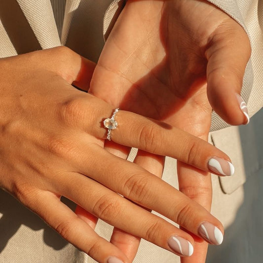 Ruce ukazující stříbrný prsten Selah s měsíčním kamenem na jemném pozadí.