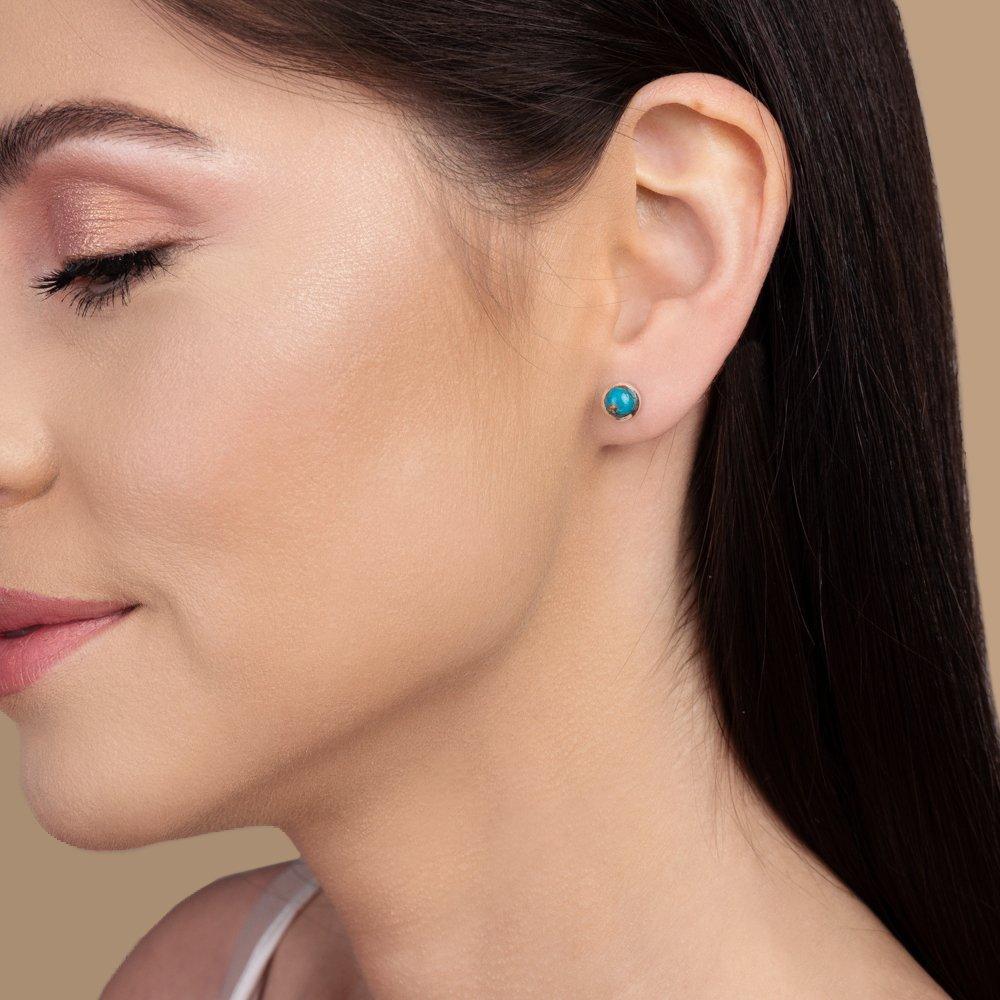 Side profile of a person wearing silver turquoise stud earrings.