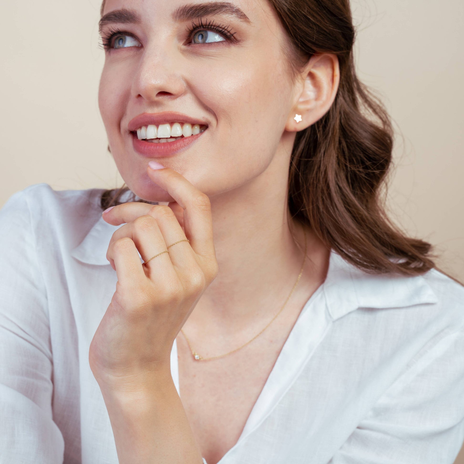 Smiling woman wearing a 14K gold chain ring and star-shaped earring.