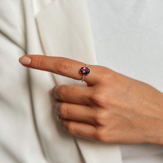 Close-up of a hand wearing a silver ring with an amethyst and zirconia stones.