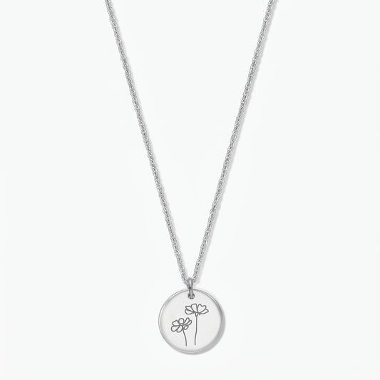 Sterling silver birthflower necklace for October (Cosmos) by Indira, with a round disc pendant engraved with two cosmos flowers on a fine silver chain, isolated on a white background.