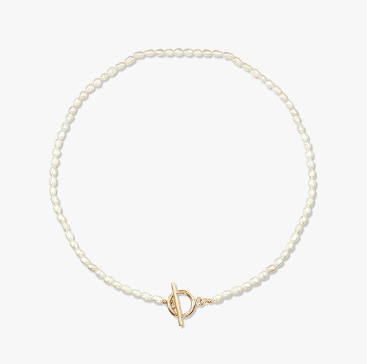 Minimalistický perlový náhrdelník se zlatou sponou na bílém pozadí.