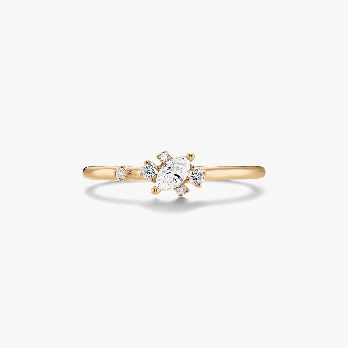 Jemný prsten ze žlutého zlata 14K se středovým diamantem brusu marquise a malými kulatými akcentními diamanty na bílém pozadí.