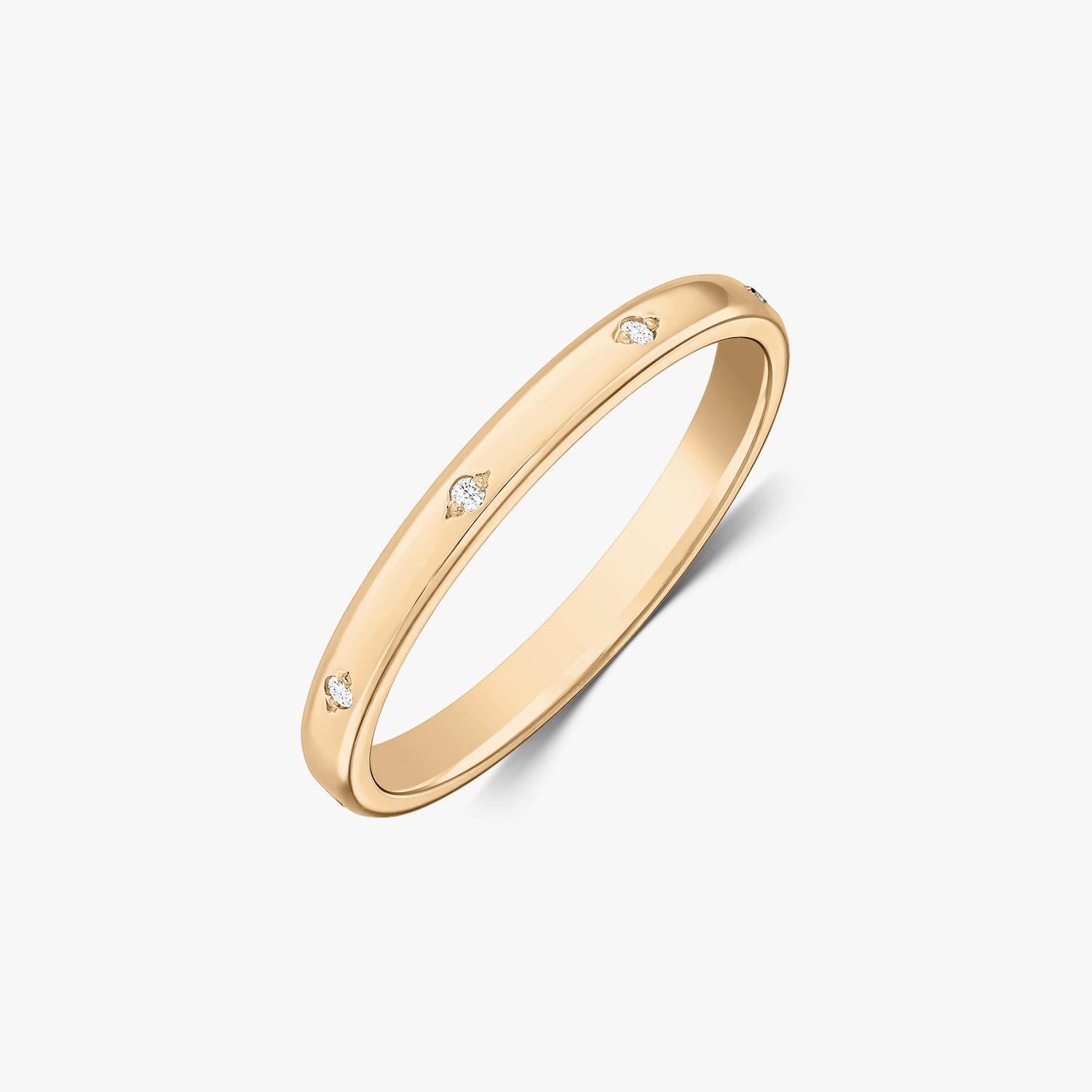 Angled studio shot of a slim 14K yellow gold wedding band with small flush-set diamond accents on a white background.