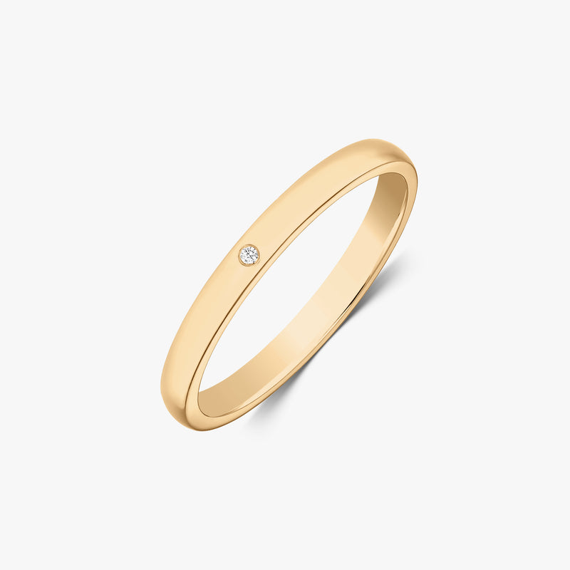 Štíhlý snubní prsten ze žlutého zlata 14k s malým kulatým diamantem v hladkém osazení, šikmý pohled na bílém pozadí.