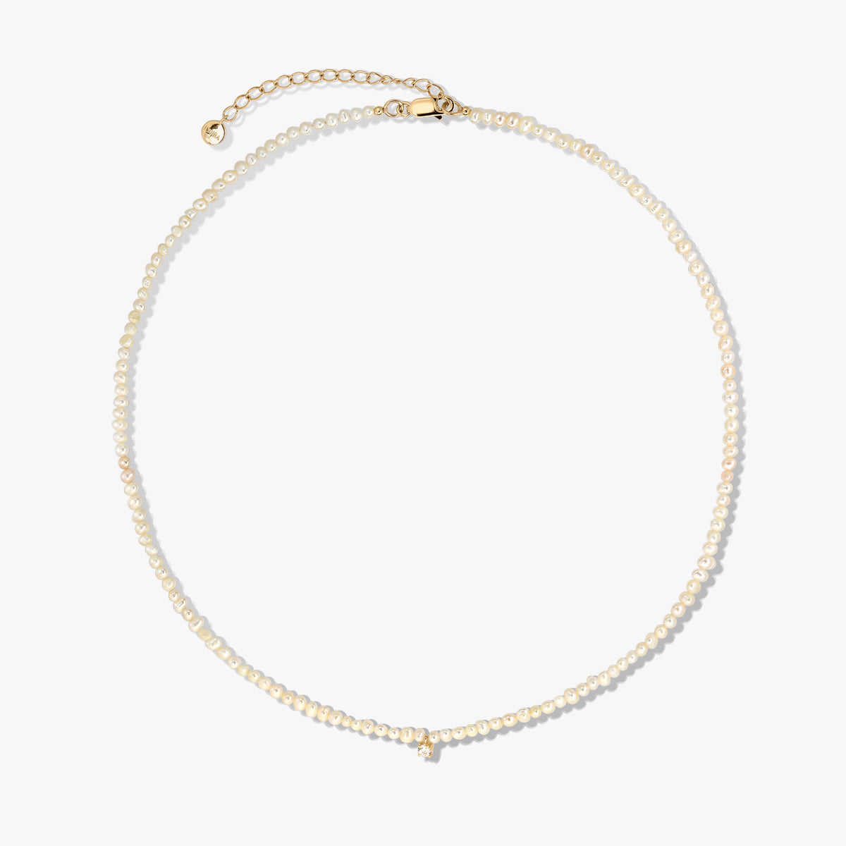 Delicate cultured pearl beaded necklace with a gold-plated sterling silver clasp and extender, photographed on a white background.