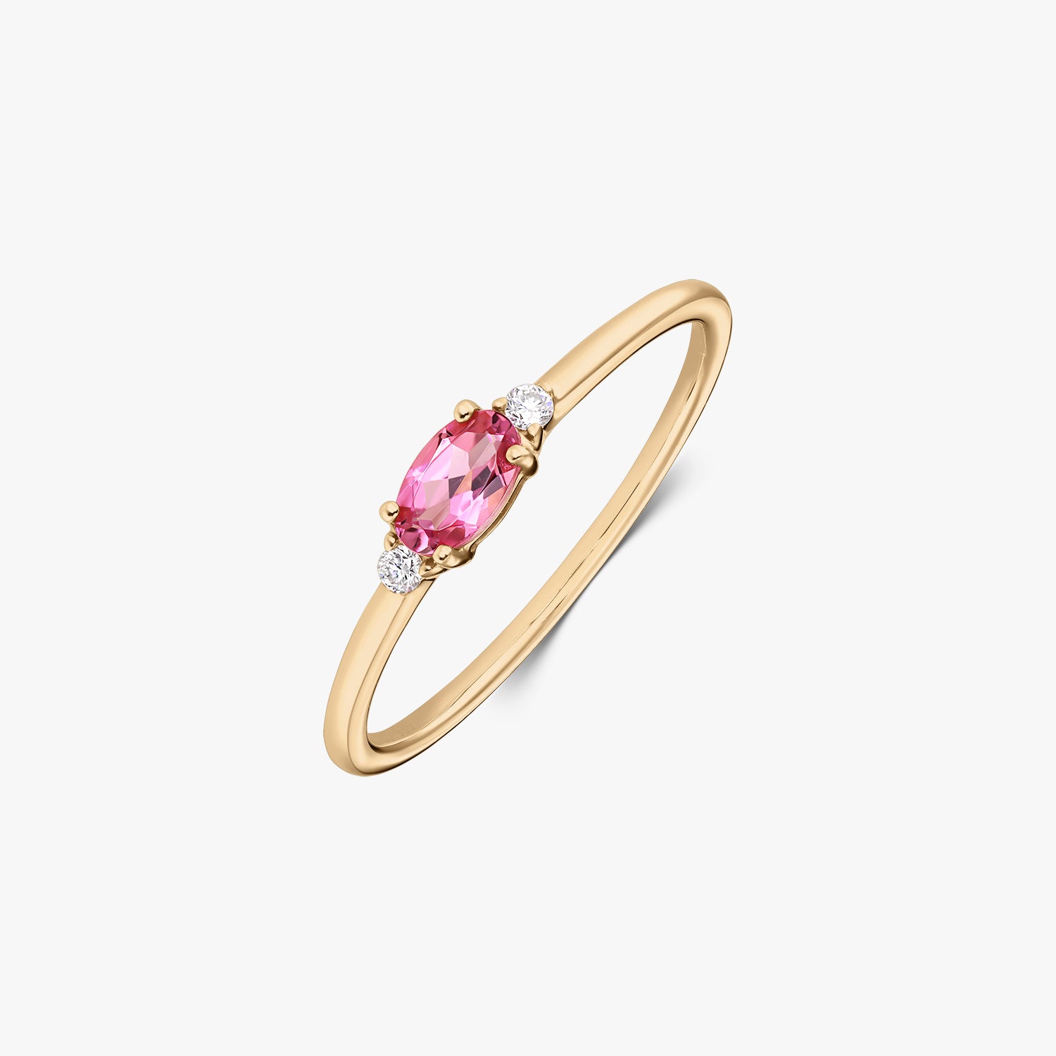Prsten ze žlutého zlata 14K s oválným růžovým turmalínem uprostřed a dvěma malými kulatými diamanty po stranách, na štíhlé obroučce, na bílém pozadí.