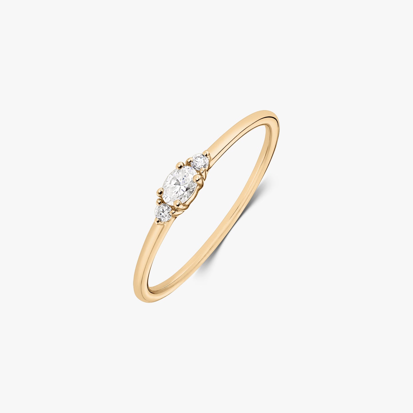 Grace 14K yellow gold ring with an oval natural diamond flanked by two small round diamonds on a slim band, isolated on a white background.