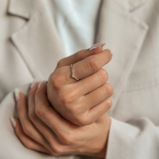 Close-up of a hand wearing a minimalist silver V-shaped ring.