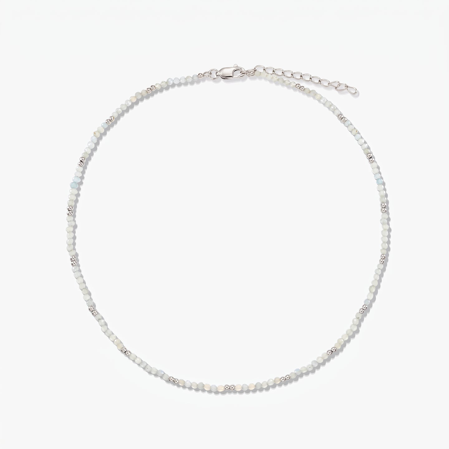 Dainty sterling silver necklace with small moonstone beads and an adjustable extender chain, photographed on a white background.