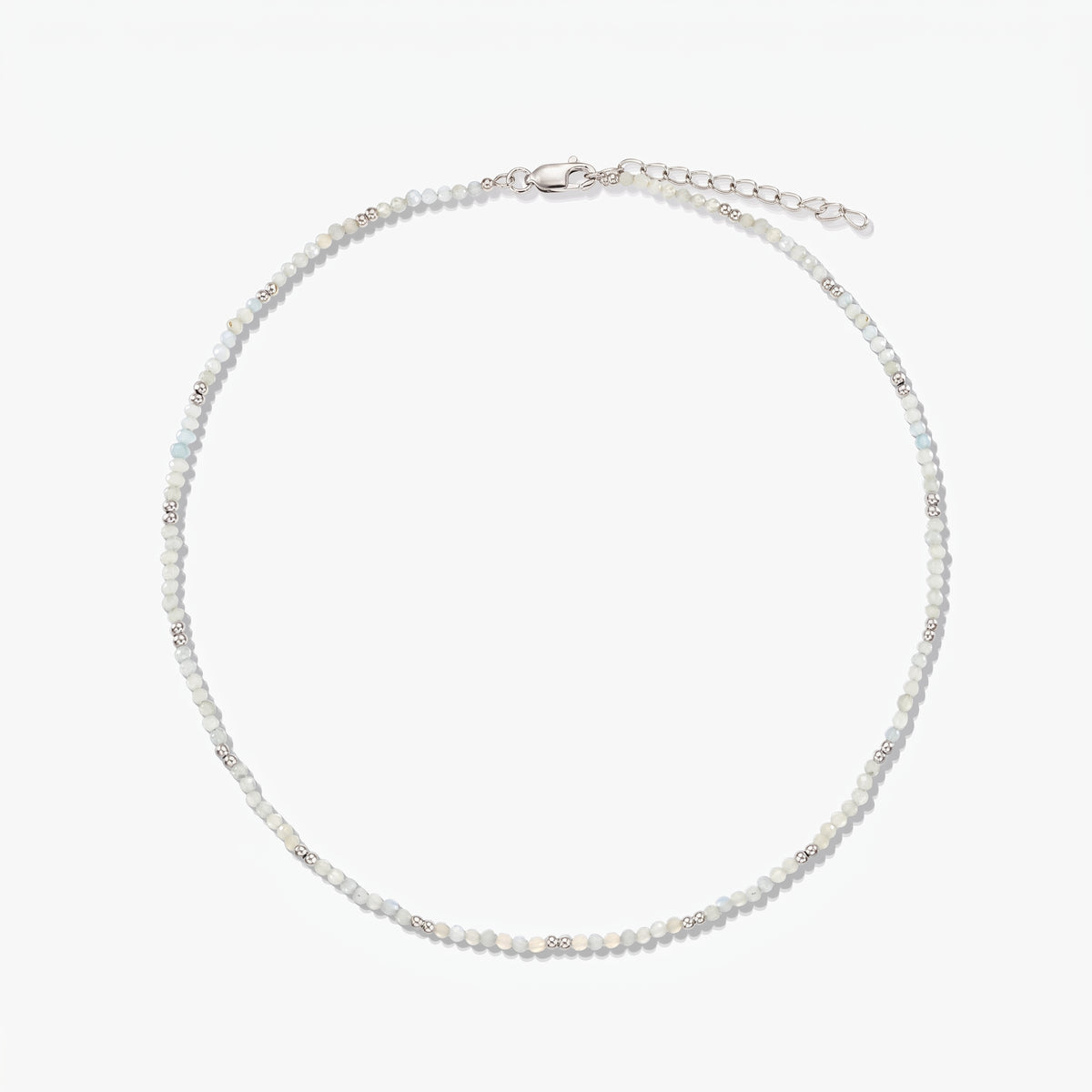 Dainty sterling silver necklace with small moonstone beads and an adjustable extender chain, photographed on a white background.