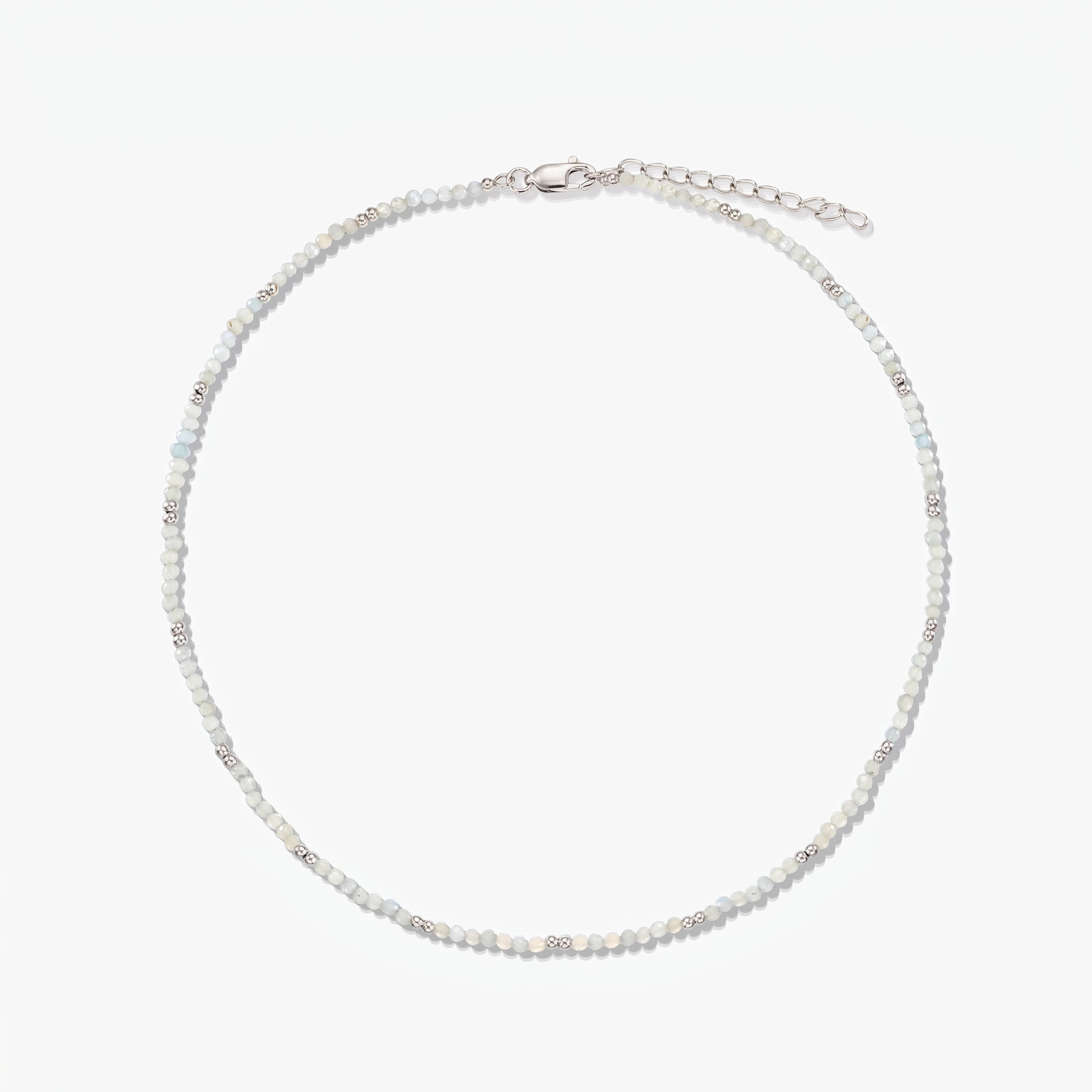 Dainty sterling silver necklace with small moonstone beads and an adjustable extender chain, photographed on a white background.