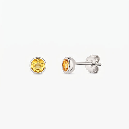 Silver stud earrings with round citrine birthstones on a white background, shown front and side with butterfly backs.