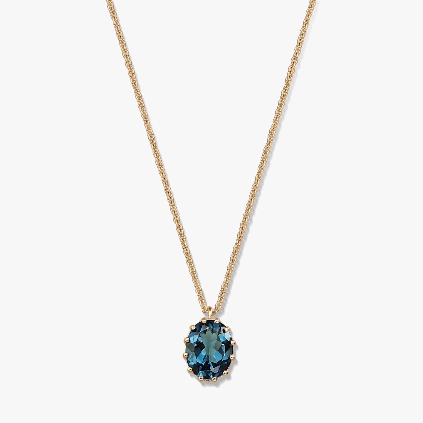 Delicate gold‑plated sterling silver necklace with an oval London blue topaz pendant on a white background.
