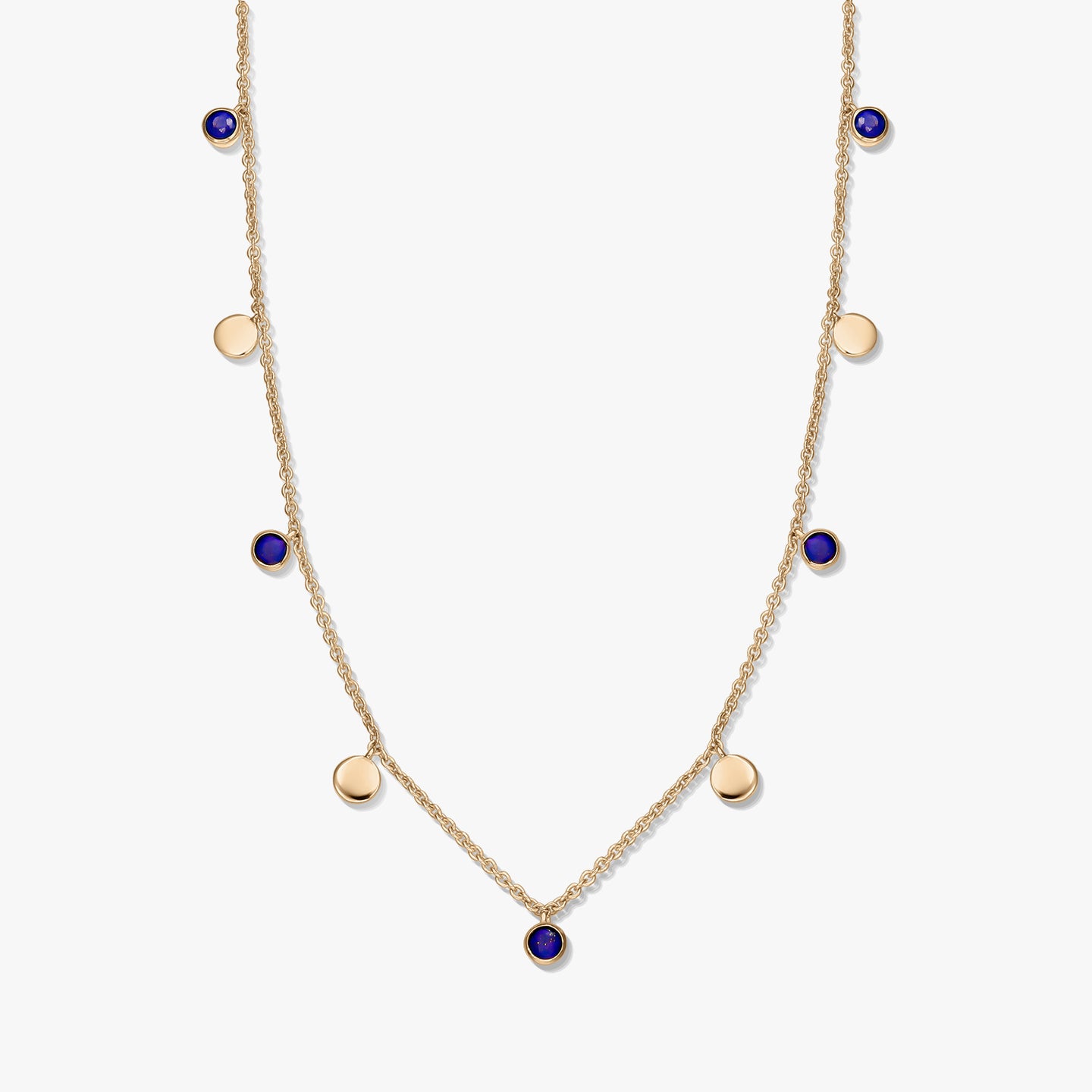 Gold‑plated sterling silver station necklace with round lapis lazuli cabochons and small gold disc charms on a delicate chain, photographed on a white background.