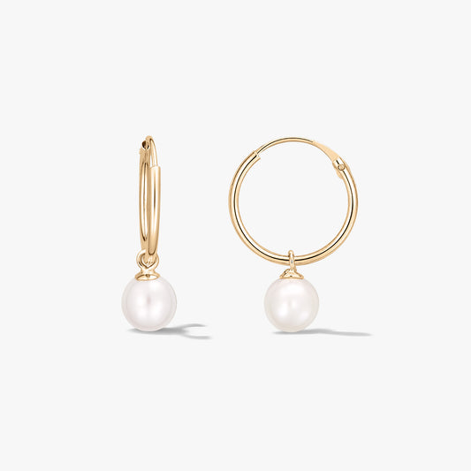 Pair of yellow gold hoop earrings with round natural white pearl drops on a white background.