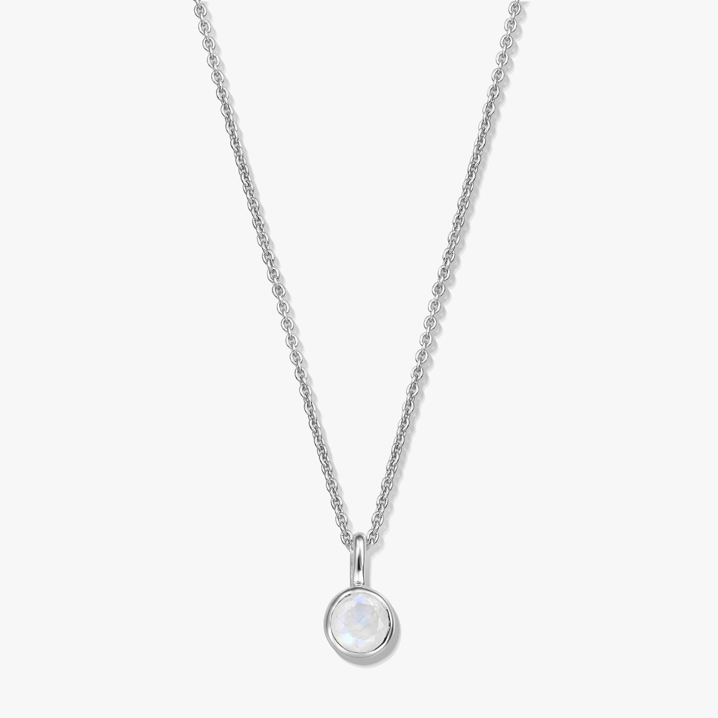 Sterling silver birthstone necklace with a round bezel-set moonstone pendant on a fine chain, photographed on a white background.