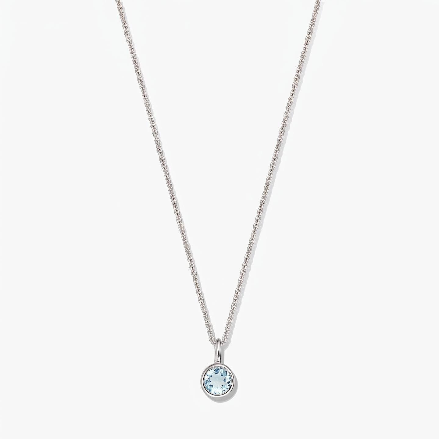 Sterling silver birthstone necklace with a small round bezel-set blue topaz pendant on a white background.