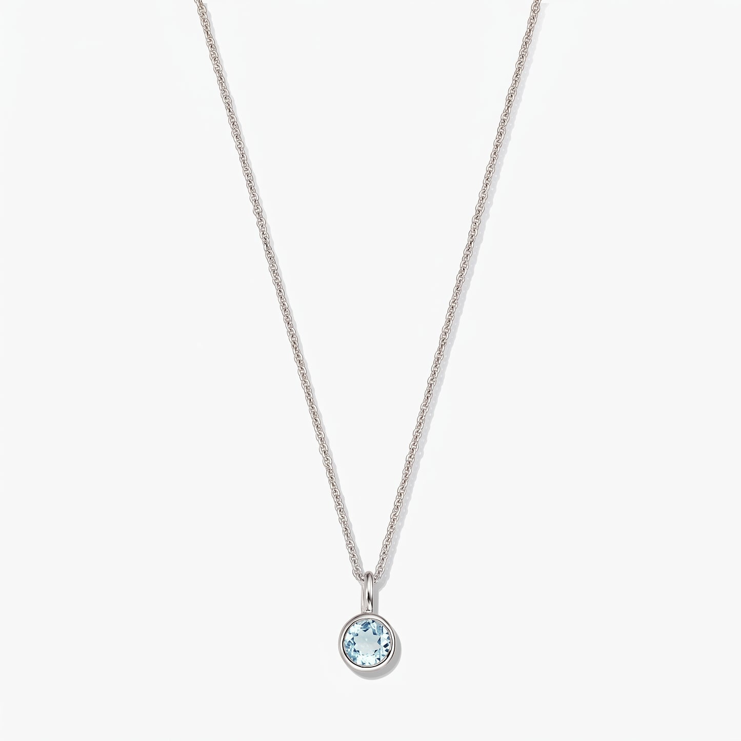 Sterling silver birthstone necklace with a small round bezel-set blue topaz pendant on a white background.