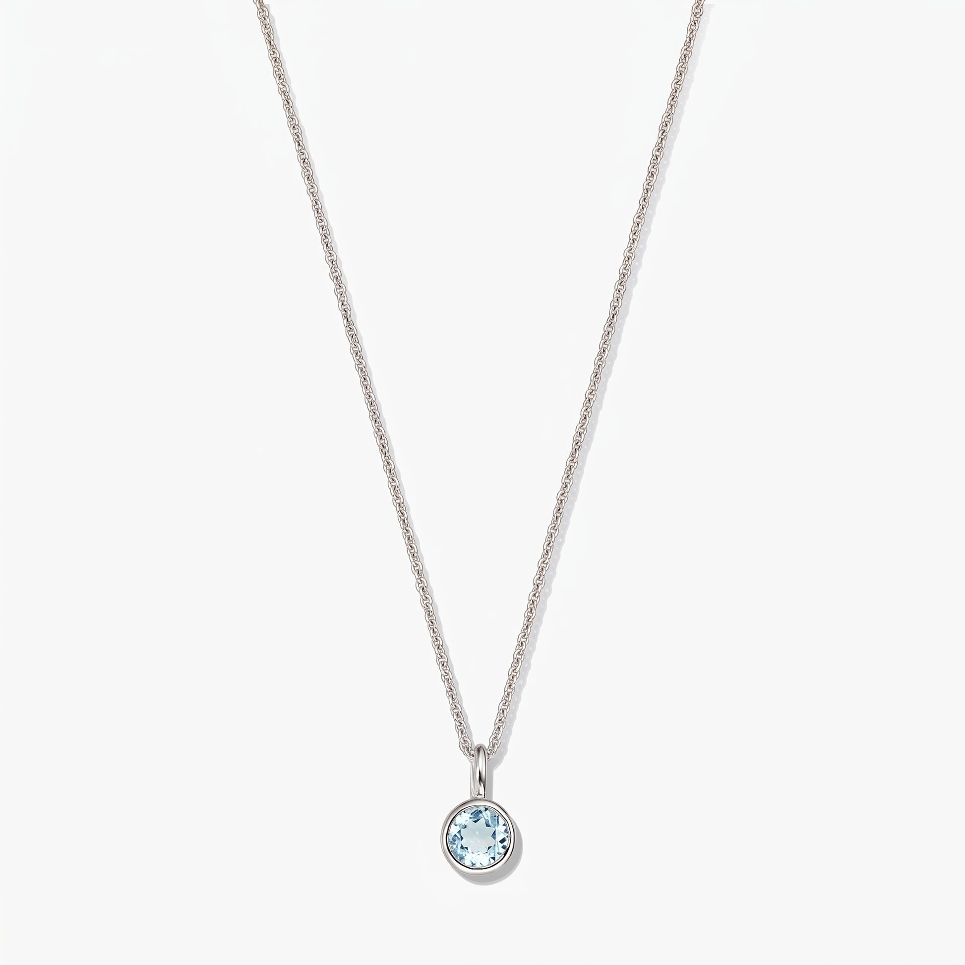 Sterling silver birthstone necklace with a small round bezel-set blue topaz pendant on a white background.