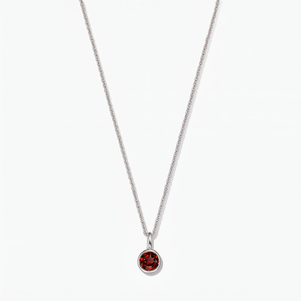 Sterling silver birthstone necklace with a round bezel‑set garnet pendant on a white background.
