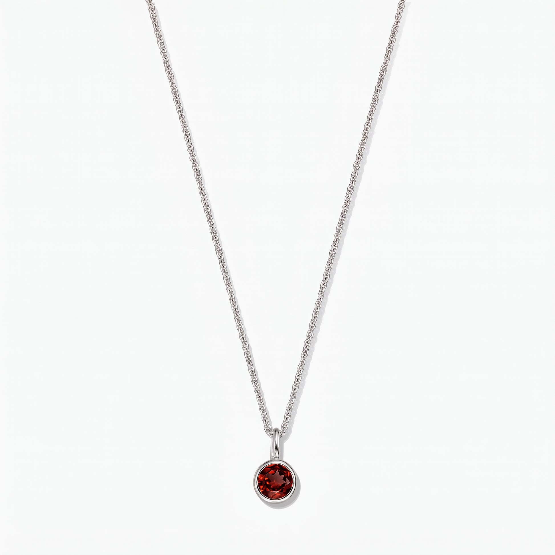 Sterling silver birthstone necklace with a round bezel‑set garnet pendant on a white background.