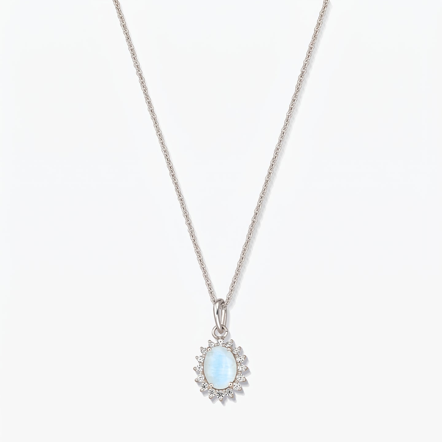 Sterling silver necklace with an oval light‑blue moonstone pendant framed by small clear stones on a fine chain, photographed on a white background.