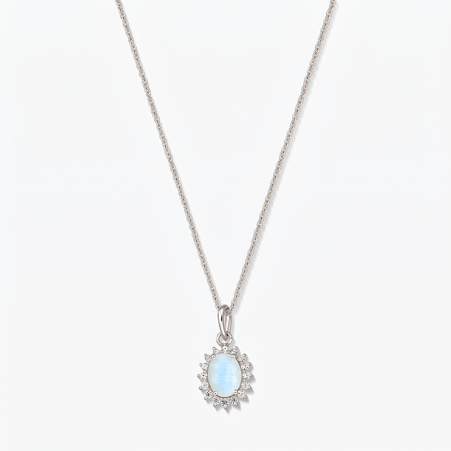 Sterling silver necklace with an oval light‑blue moonstone pendant framed by small clear stones on a fine chain, photographed on a white background.