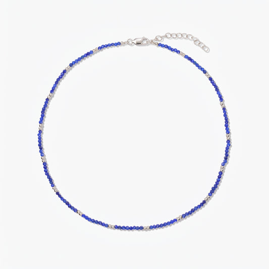 Stříbrný náhrdelník Indira SummerScape s modrými korálky z lapisu lazuli, karabinovým zapínáním a prodlužovacím řetízkem na bílém pozadí.
