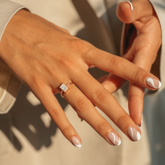 Close-up of hands modeling a rose gold ring with a moonstone
