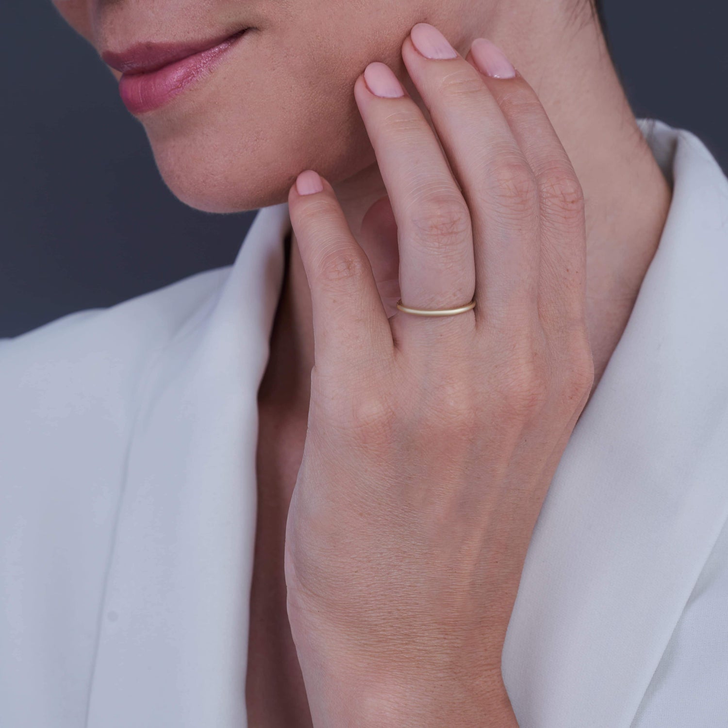Woman's hand resting on chin wearing a Layla Gold-Plated Silver Ring on her middle finger, with a soft smile.