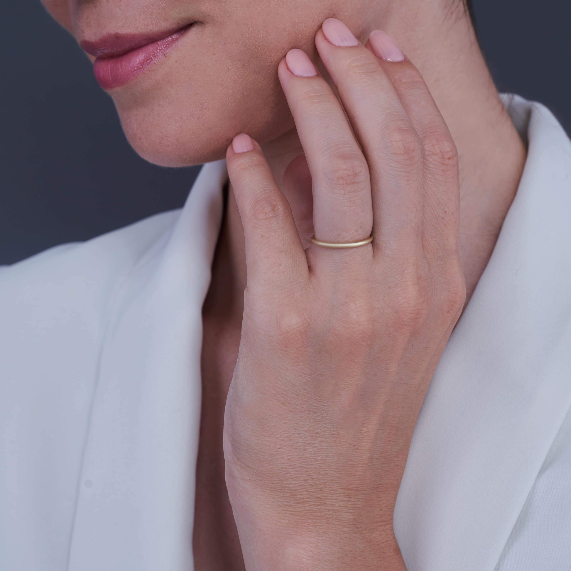 Woman's hand resting on chin wearing a Layla Gold-Plated Silver Ring on her middle finger, with a soft smile.