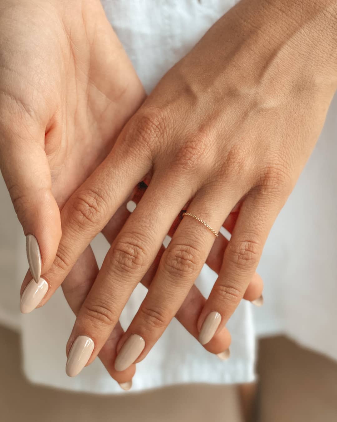 Close-up of hands with manicured nails wearing a 14K gold chain ring.